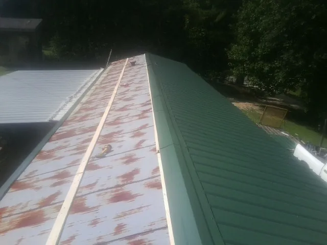 Old rusted panels beside newly installed green metal roofing — Wind Damage Roof Repair by Roofing Brothers in Bluff City