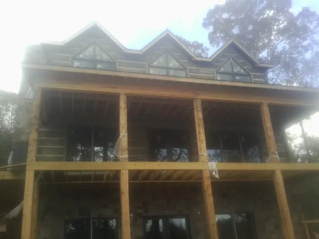 Dormers and porch framing on a large log home under construction — Roof Coating work by our crew in Bluff City