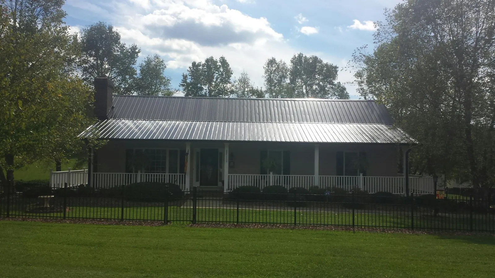 Gray metal roof on a brick ranch with a full width front porch — Gutter Guard Installation work by our crew in Bluff City