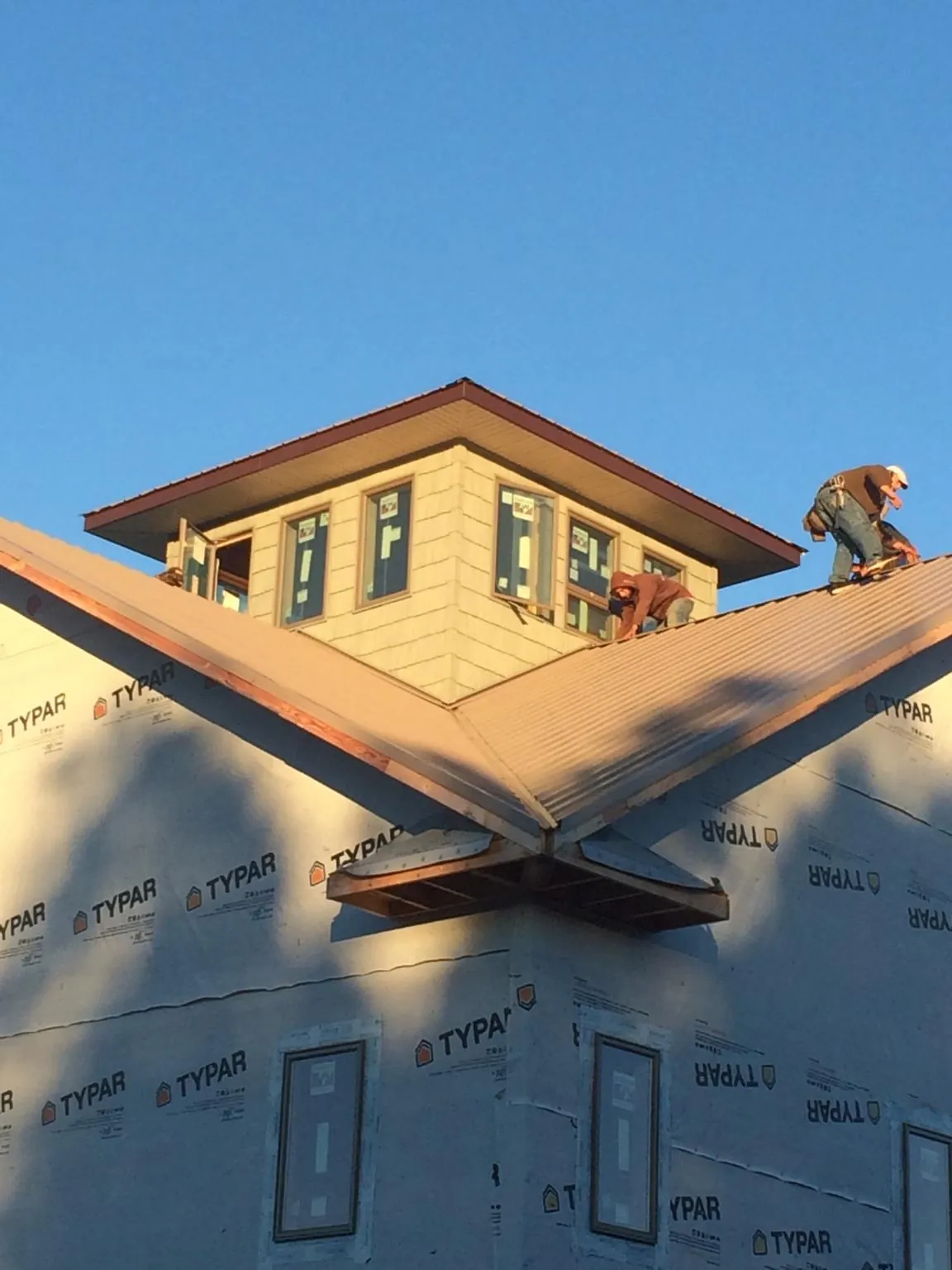 Roofers working around a rooftop cupola on a new metal roof at sunset — Roof Waterproofing in Bluff City by Roofing Brothers